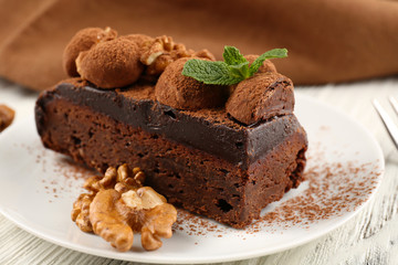 Piece of chocolate cake with walnut and mint on the table, close-up