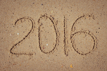 New year 2016 written on the sand.