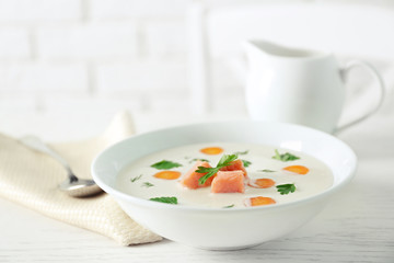 Delicious cream soup with salmon and carrot in white bowl