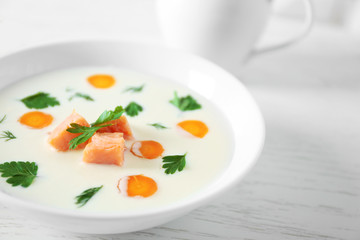 Delicious cream soup with salmon and carrot in white bowl
