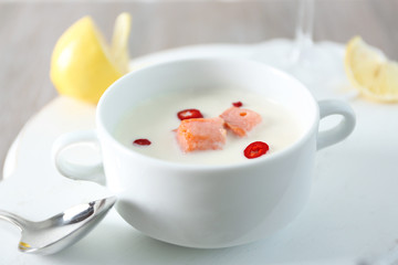 Tasty salmon cream soup, wine and lemon on wooden table, close up