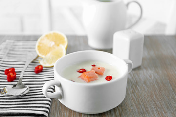 Tasty fish cream soup, lemon, salt and striped cotton serviette on wooden table, close up