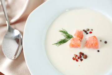 Delicious salmon cream soup with spoon on wooden table, close up