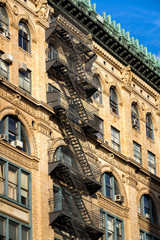 Fototapeta premium Typical late 19th century Soho brick building with fire escape, ornate facade and copper cornice. Manhattan, New York City