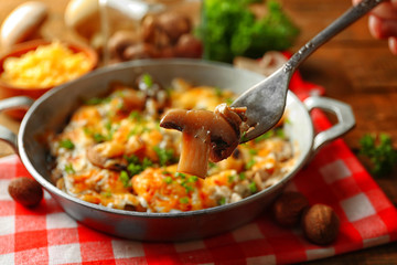 Roasted mushrooms, chicken and cheese gratin in pan, on wooden background