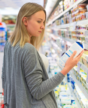 Woman choosing milk in grocery store.