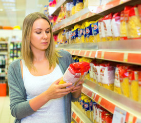 Woman choosing pasta in grocery store.