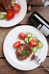 Roasted beef fillet and fresh vegetables on plate, on wooden background