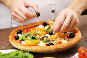 Cook making delicious pizza at the restaurant, close-up