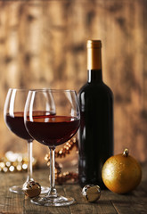 Red wine and Christmas ornaments on wooden table on wooden background