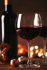 Red wine and Christmas ornaments on wooden table on wooden background