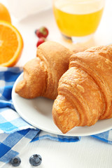 Fresh tasty croissants with berries on white wooden background