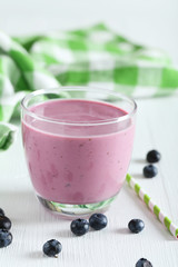 Fresh blueberry smoothie in the glass on white wooden background