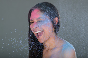 Beautiful young brunette girl with colorful powder blowing in her face