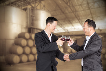 Two Asian business man holding a glass of wine and handshaking