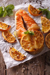 baked salmon with oranges closeup on baking paper. vertical top view
