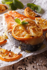 baked salmon steak with oranges closeup on baking paper. Vertical
