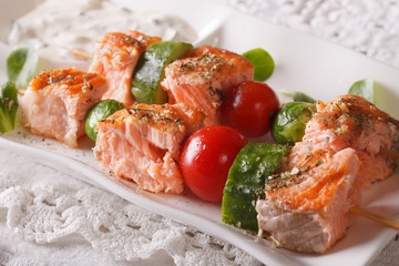 Tasty salmon kebab with vegetables close-up on a plate. horizontal
