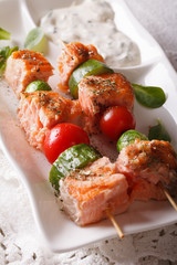 Grilled salmon on skewers close-up on a plate and sauce. vertical
