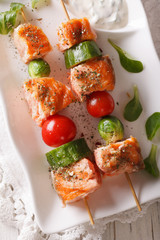 Grilled salmon on skewers close-up on a plate. vertical top view
