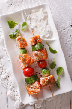Salmon kebab with vegetables close-up on a plate. vertical top view

