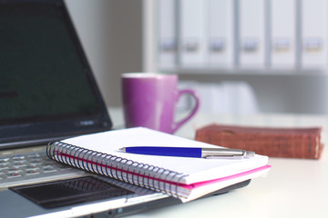Office table with blank notepad and laptop 