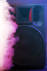 Black loudspeaker in a smoke on dark background