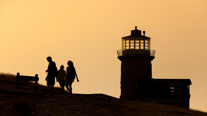 Silhouette of some people and a lighthouse in England