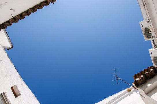 A Corner Of Blue Sky Surrounded By White House, Copy Space In The Middle