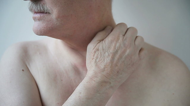 Shirtless man scratches his irritated neck.
