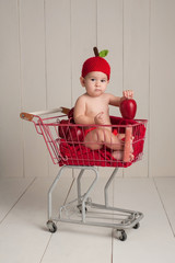 Baby Sitting in a Shopping Cart Wearing an Apple Hat