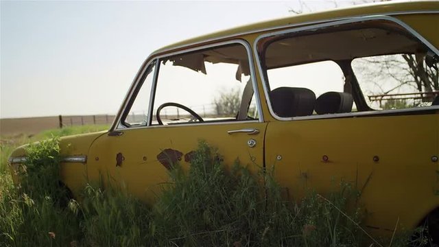 An old broken down car sits abandoned in a field