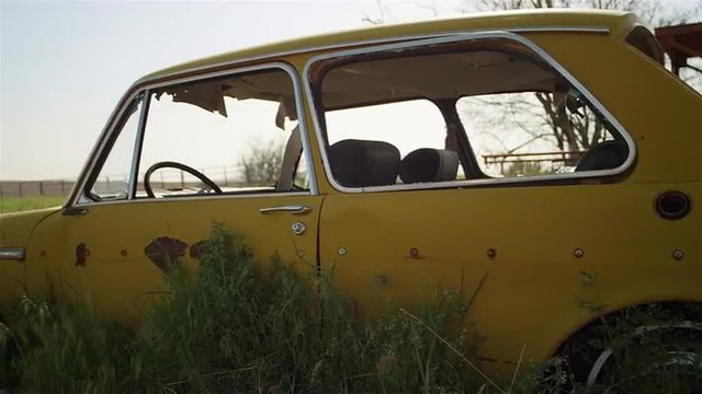 An old broken down car sits abandoned in a field