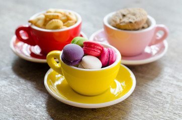 macaroons and cookies in cup on wooden table