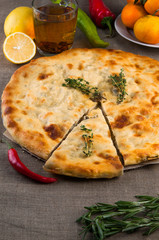 Top view of calzone pizza or chicken mushroom pie with pepper, lemon, rosemary and tea on linen fabric background
