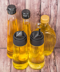 Sesame seed oil, flax seed oil, olive oil, corn oil and vegetable oil in bottles over wooden background