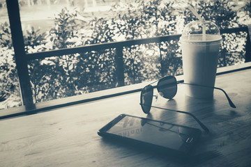 Iced coffee with smart phone and sunglass at cafe