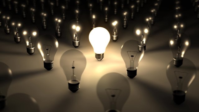 A sea of dark lightbulbs is contrasted by a single brilliantly illuminated lightbulb. Can be used to portray the concepts of creativity, standing out, a brilliant idea or person, and many more! 