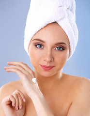 Young woman  putting cream on her hand Isolated on gray background