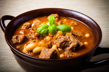 Traditional turkish meal - Kuru fasulye in a clay bowl on a ligh