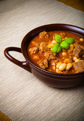 Traditional turkish meal - Kuru fasulye in a clay bowl on a ligh