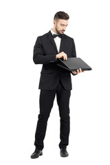 Young businessman opening laptop. Full body length portrait isolated over white studio background. 