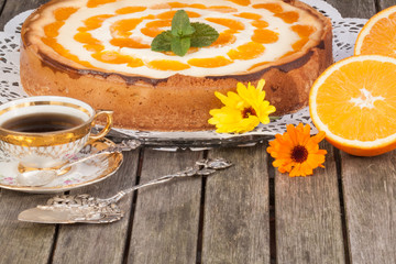 Mandarinen-Käsetorte mit Mokkatasse auf Holztisch, horizontal