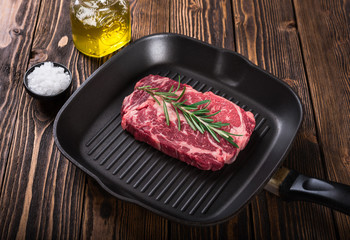 Raw marbled meat steak Ribeye on grill pan on dark wooden background