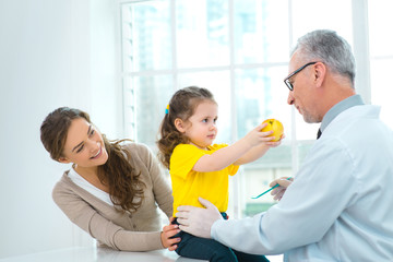 Aged doctor with little patient in hospital office