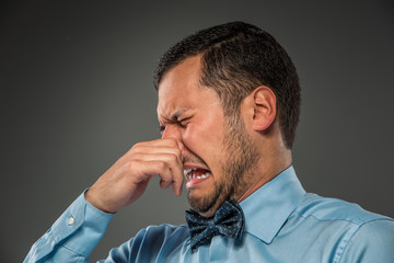 Young man - disgusted expression closing his nostrils with finge