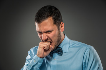 Portrait of an angry guy biting his fist. Human emotion.