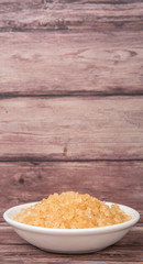Brown sugar in white bowl over wooden background