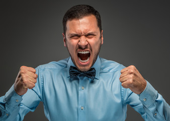 Portrait angry upset young man in blue shirt, butterfly tie 