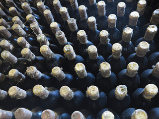 Old dirty wine bottles stacked up in cellar